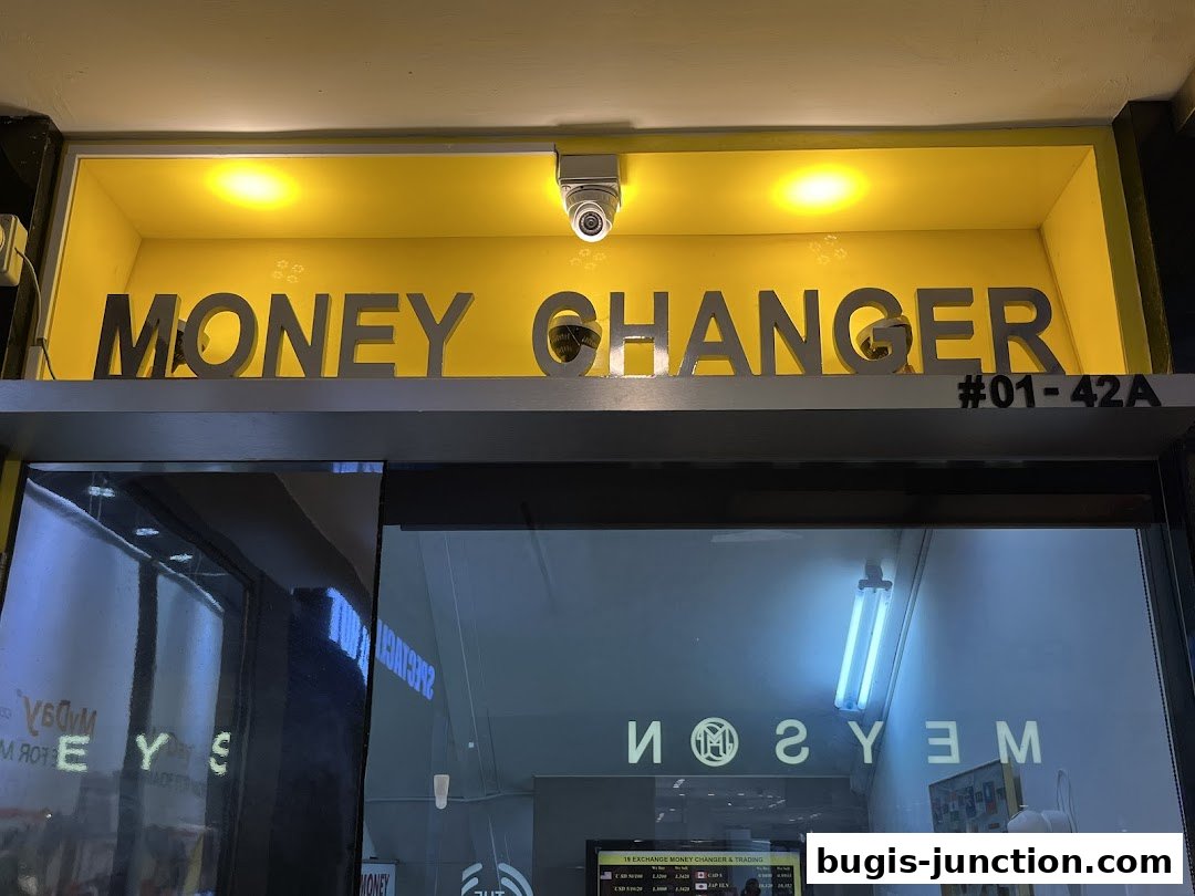 The exterior of a money changer shop with prominent signage and security cameras.