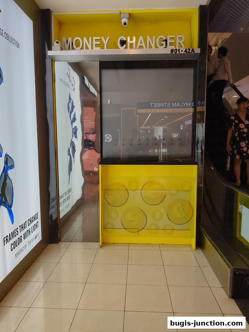 The exterior of a bright yellow money changer shop with signage and security cameras.