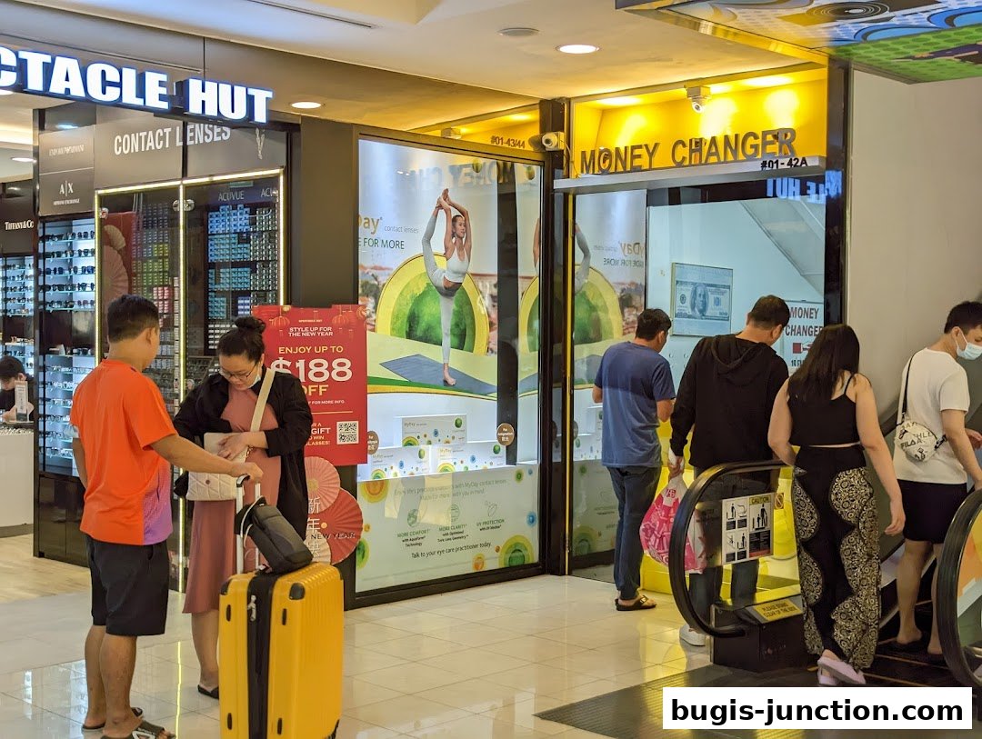 People are seen entering a money changer shop and an adjacent optical shop.