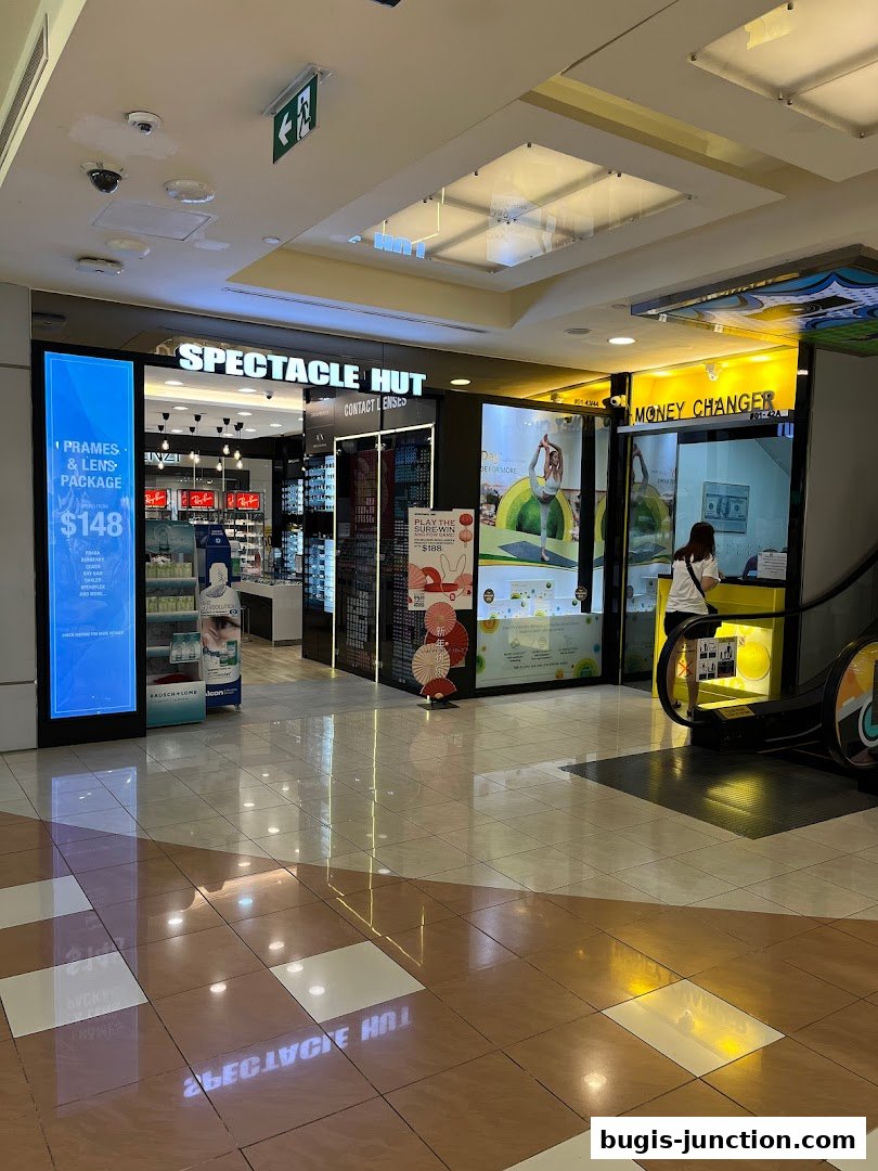 The exterior of Spectacle Hut and a Money Changer shop with an escalator.