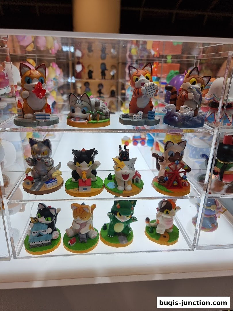 A display case filled with various cute cat figurines in different poses and outfits.