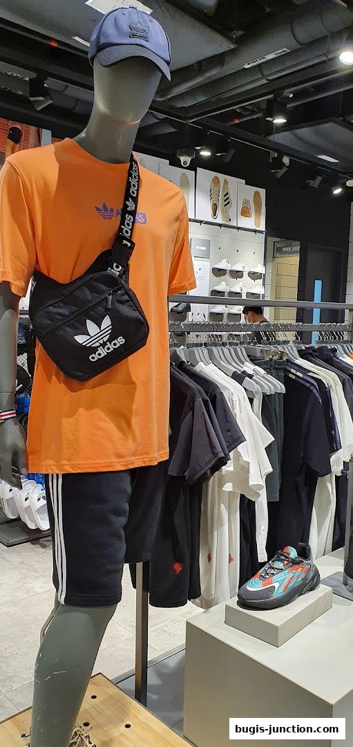 Mannequin wearing Adidas outfit with apparel and shoes displayed in store.