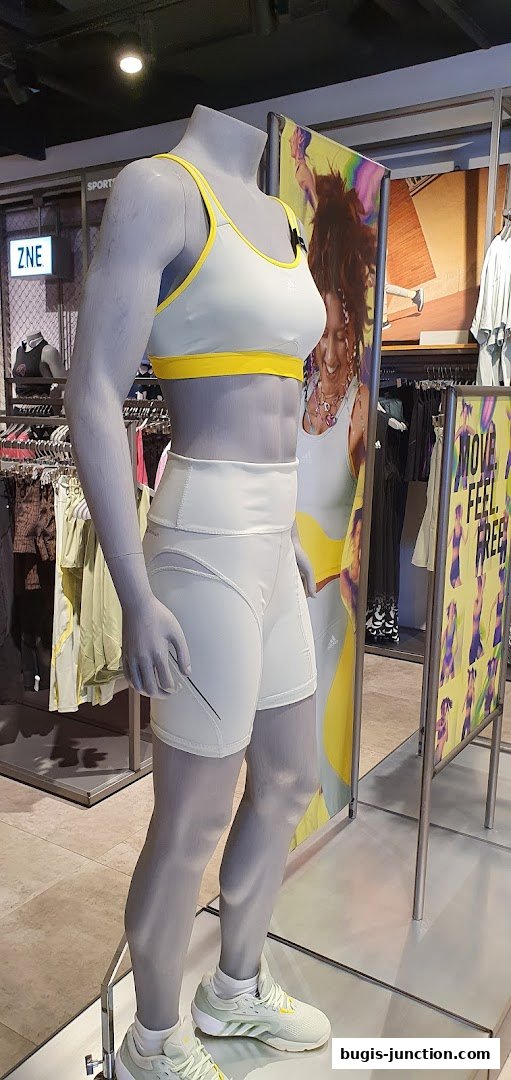 Mannequin wearing Adidas sportswear, with store displays and signage in the background.