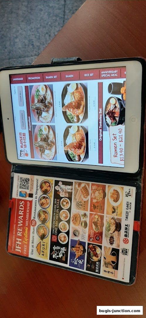 A tablet displaying the Ajisen Ramen menu with various ramen dishes and promotions.