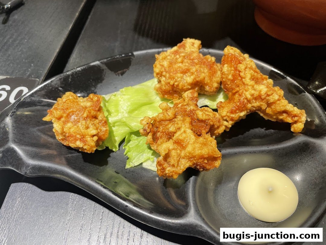 Crispy fried chicken pieces served on a black plate with lettuce and a dollop of sauce.