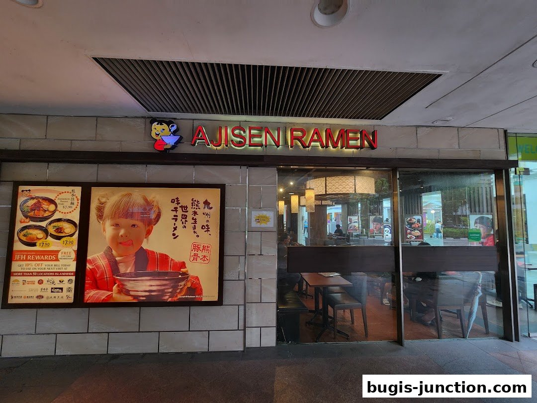 The exterior of Ajisen Ramen Bugis Junction with a prominent sign and a promotional poster.
