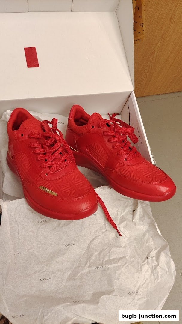 A pair of vibrant red ALDO sneakers with embossed detailing, presented in an open box.