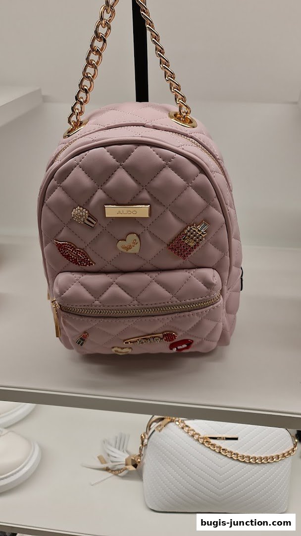 A pink quilted backpack with decorative pins and a gold chain strap from ALDO.
