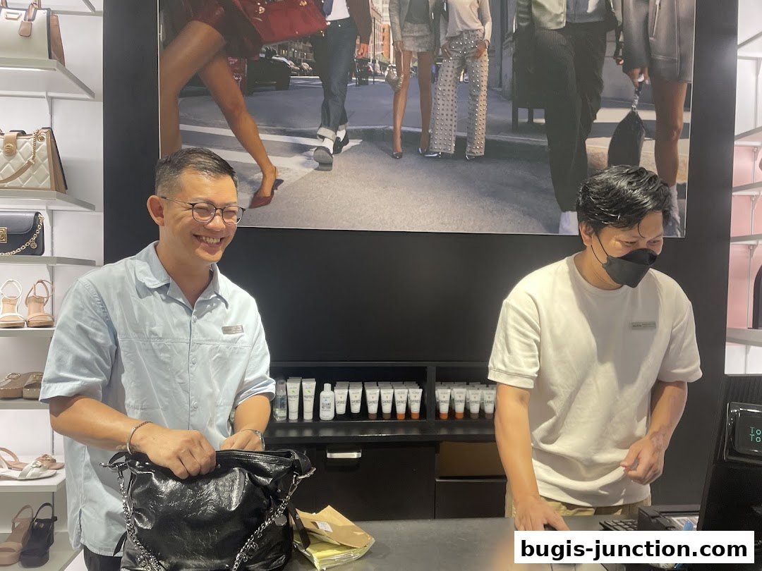 Two staff members are working at the counter of an ALDO store, with merchandise displayed on shelves.