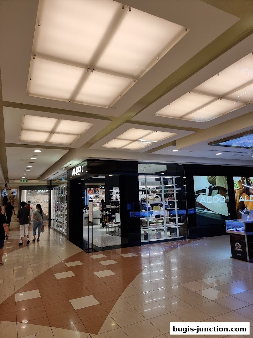 The ALDO store entrance and display windows showcasing handbags and shoes in a shopping mall.
