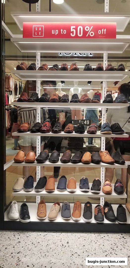 A display window showcasing a variety of men's shoes with a 'Sale up to 50% off' sign.