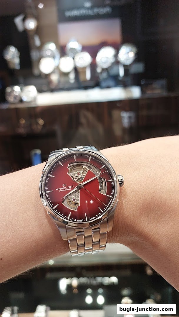 A person wearing a red-faced Hamilton automatic watch with a visible movement.