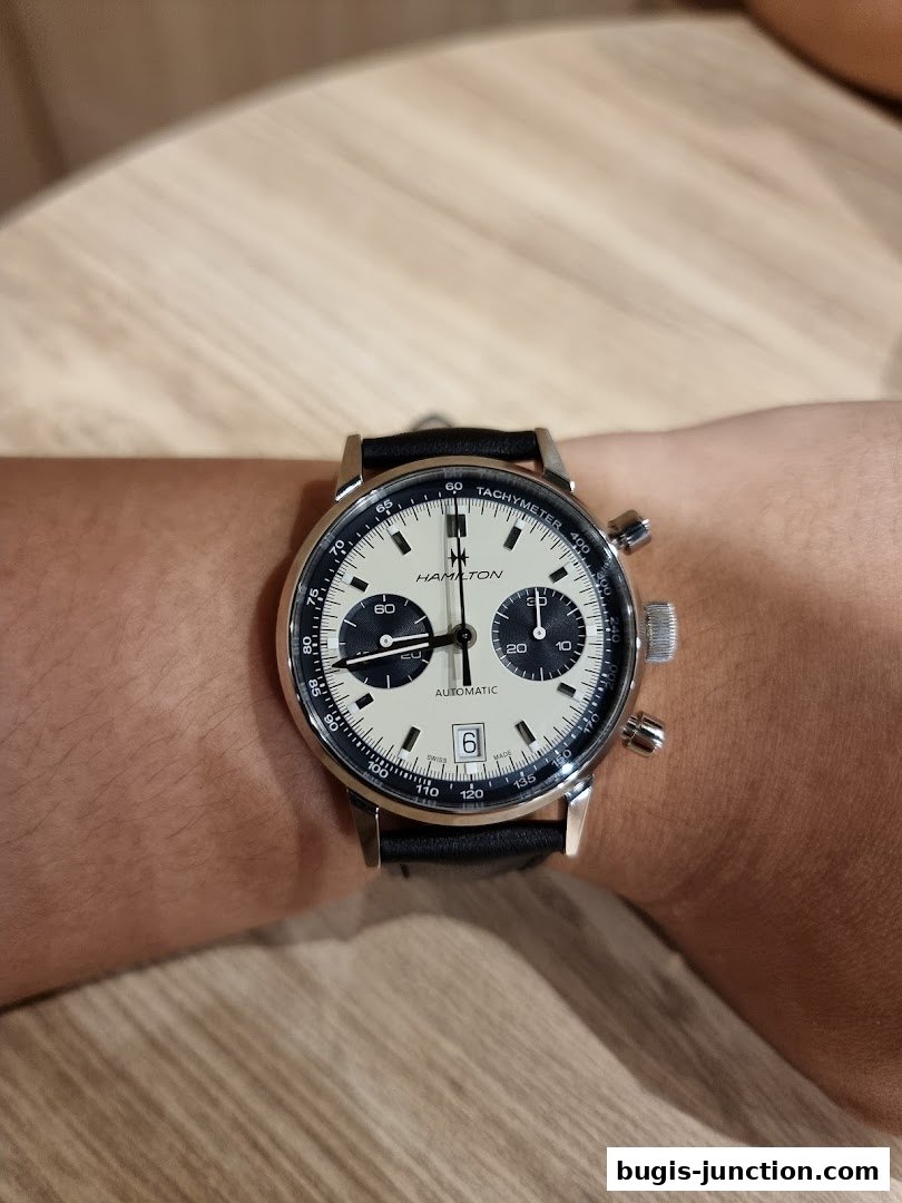 A close-up shot of a Hamilton automatic watch with a cream dial and black strap on a wrist.