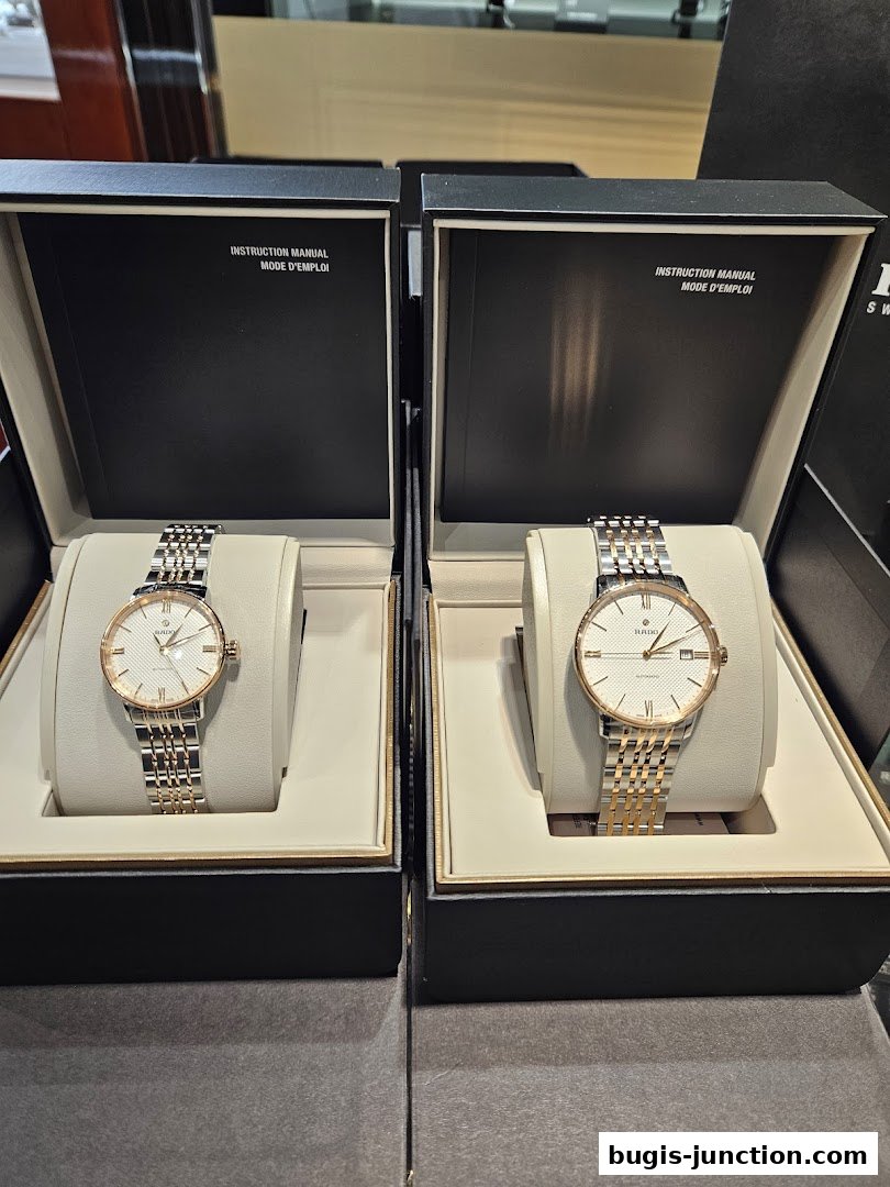 Two elegant Rado watches displayed in their boxes, featuring silver and rose gold accents.