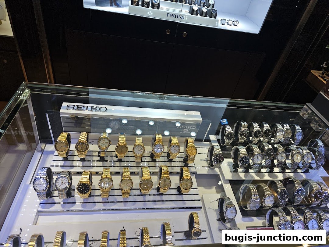 A display case filled with various Seiko and other brand watches, featuring gold and silver tones.