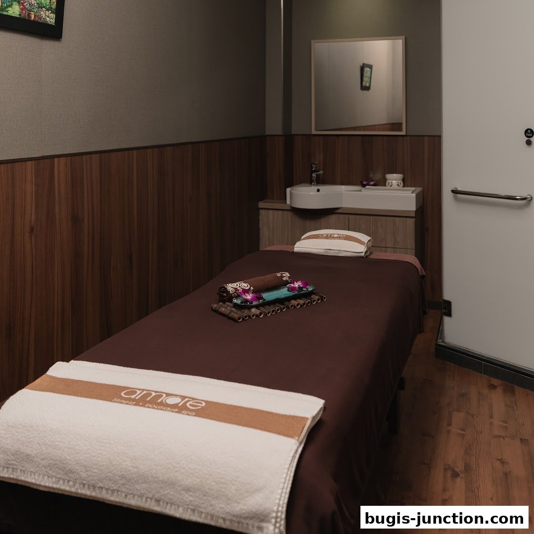 A clean and serene spa room with a massage bed, towels, and a sink area.
