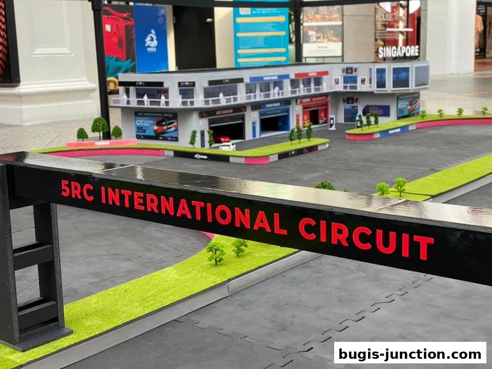 A miniature RC car racing circuit with a building facade and signage.