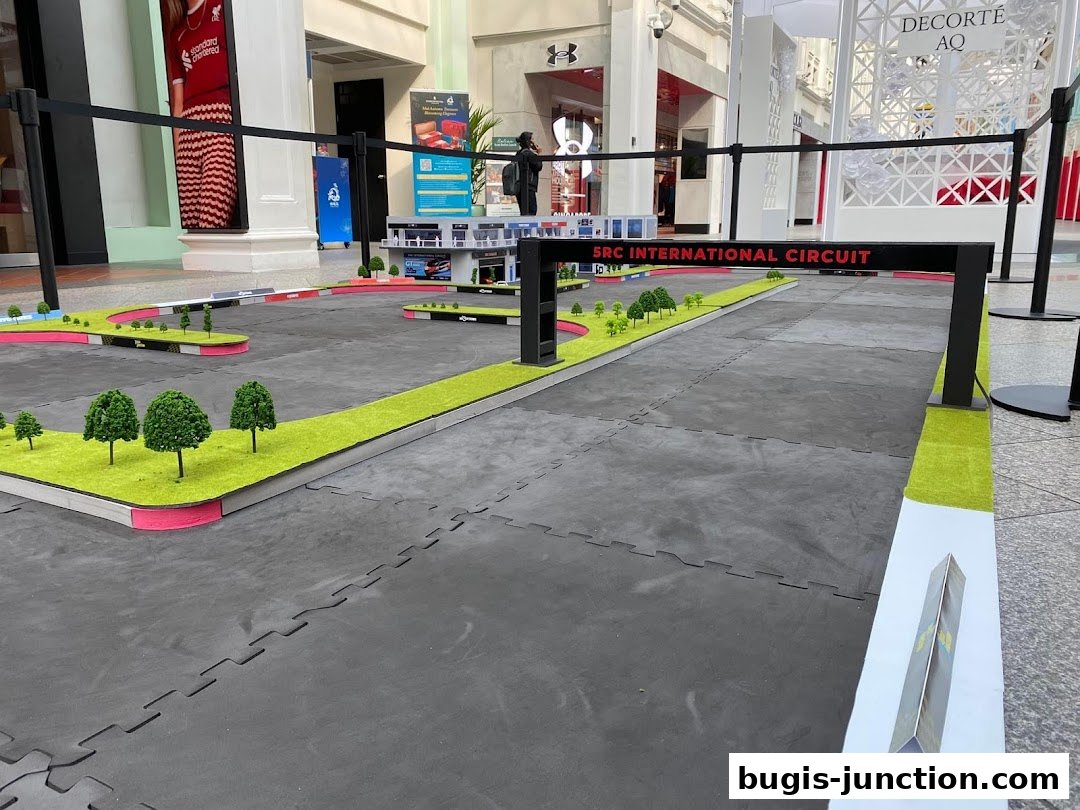 A miniature race track setup with artificial grass and trees in a shopping mall.