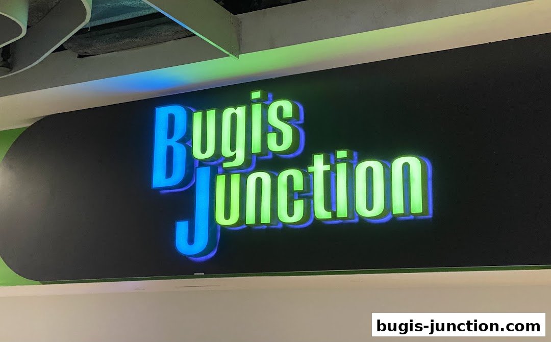 A brightly lit sign with the words "Bugis Junction" in blue and green neon letters.