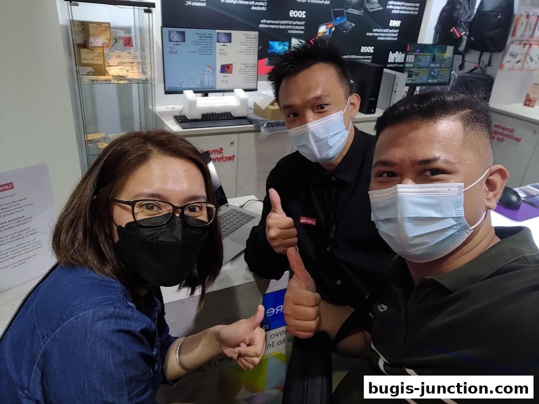 Three people wearing masks give thumbs up in a tech store.