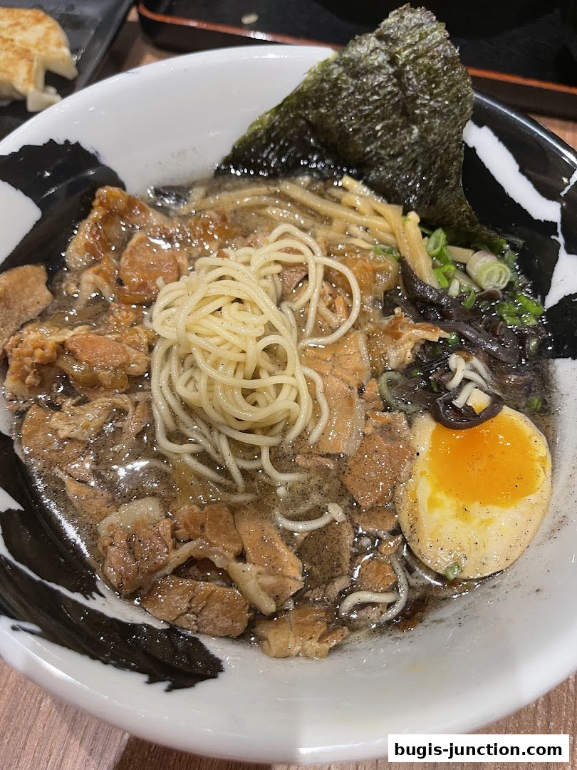 A close-up of a steaming bowl of ramen with tender pork, noodles, and a perfectly cooked egg.