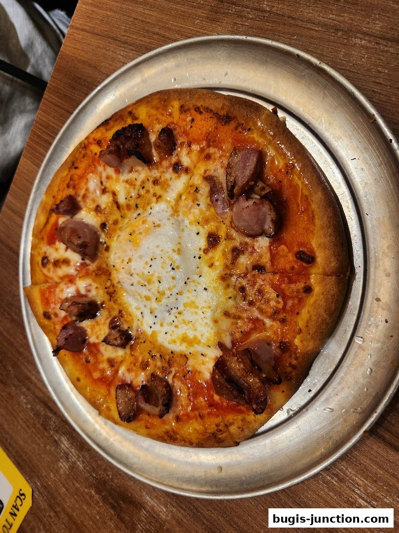 A close-up shot of a delicious pizza with sausage and a fried egg in the center.