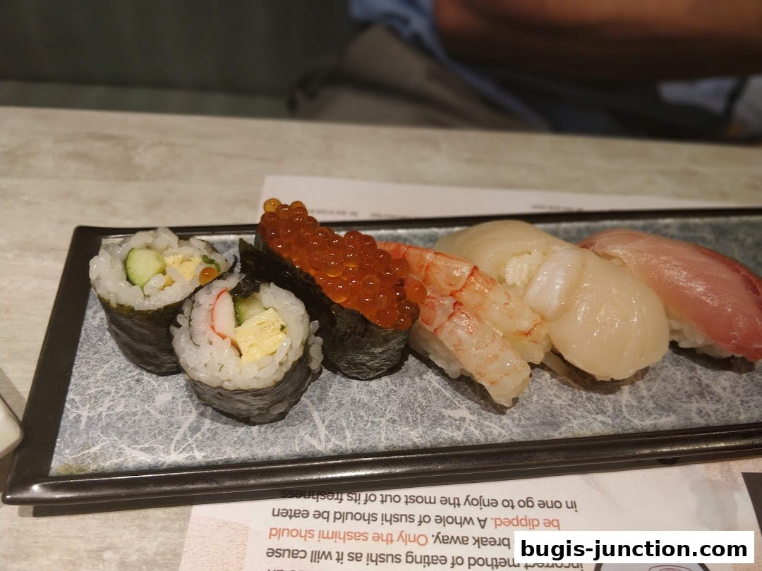 A platter of assorted sushi, including maki rolls, ikura, shrimp, scallop, and tuna nigiri.