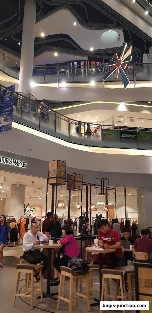 People dining and shopping in a modern, multi-level mall with stylish architecture.