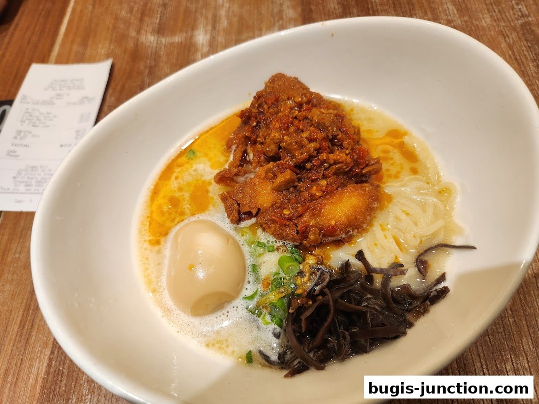 A bowl of Japanese ramen with chicken, egg, noodles, and mushrooms, with a receipt in the background.