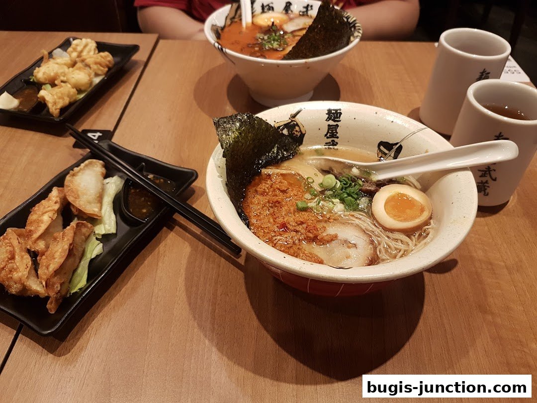 Two bowls of ramen and fried dumplings served on a wooden table.