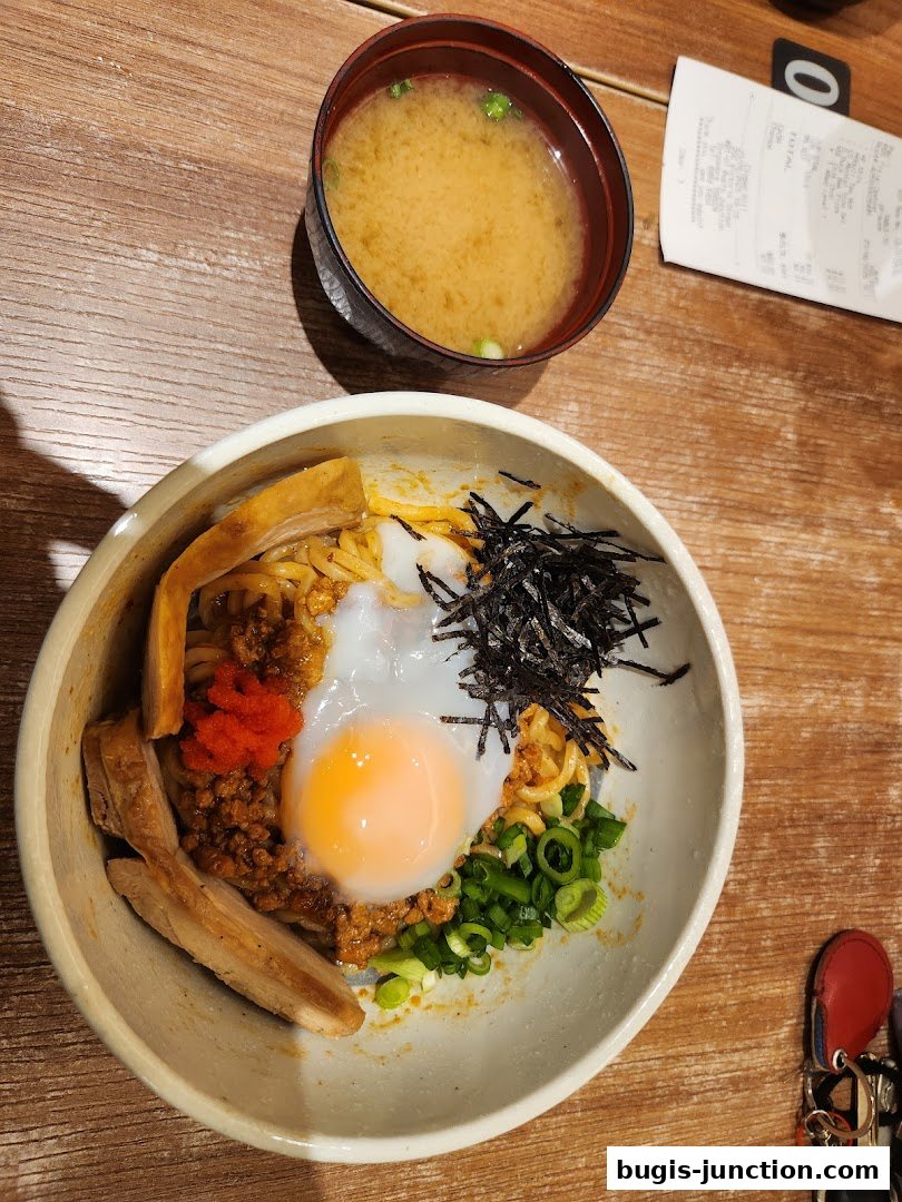 A bowl of Japanese ramen with a soft-boiled egg and a side of miso soup.
