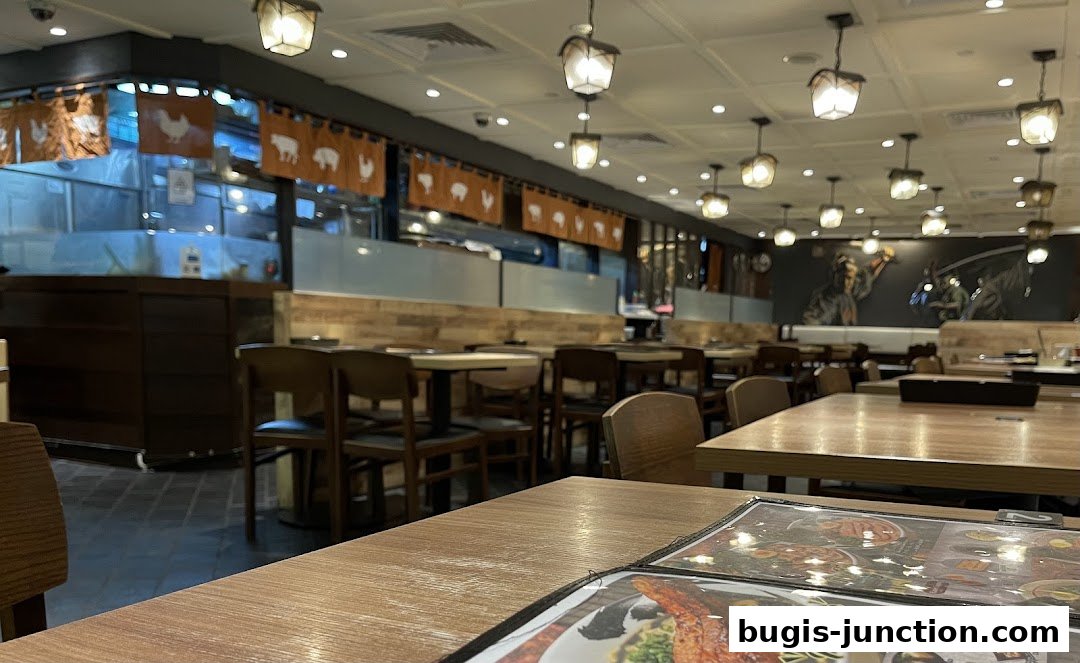Interior view of a Japanese restaurant with tables, chairs, and decorative banners.