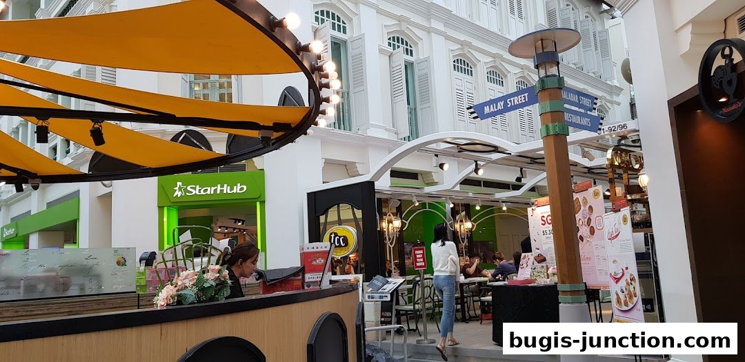 A street view of a shopping area with various shops and restaurants, including StarHub and Nando's.