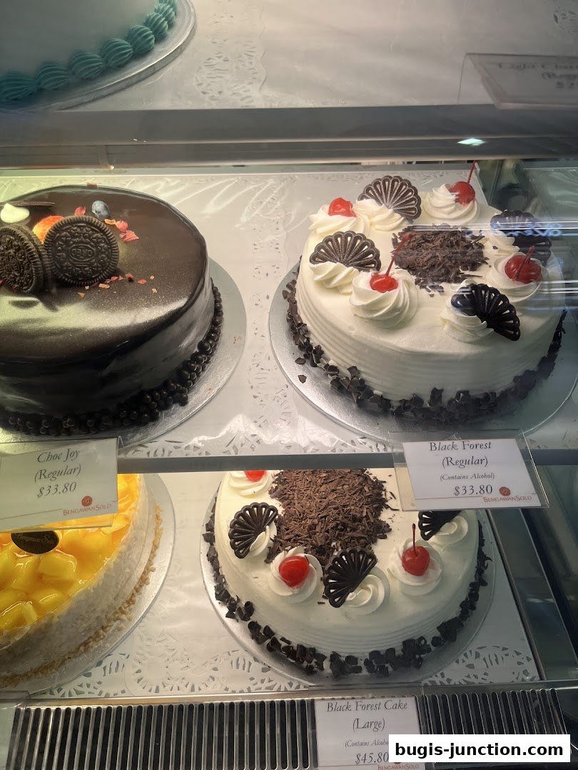 A display case filled with beautifully decorated cakes, including chocolate and Black Forest varieties.