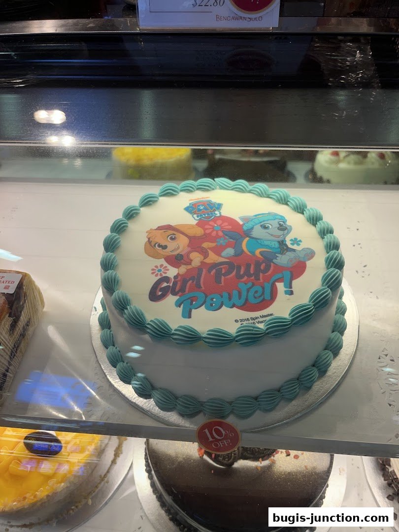 A white cake decorated with Paw Patrol characters and the text 'Girl Pup Power!' is displayed.