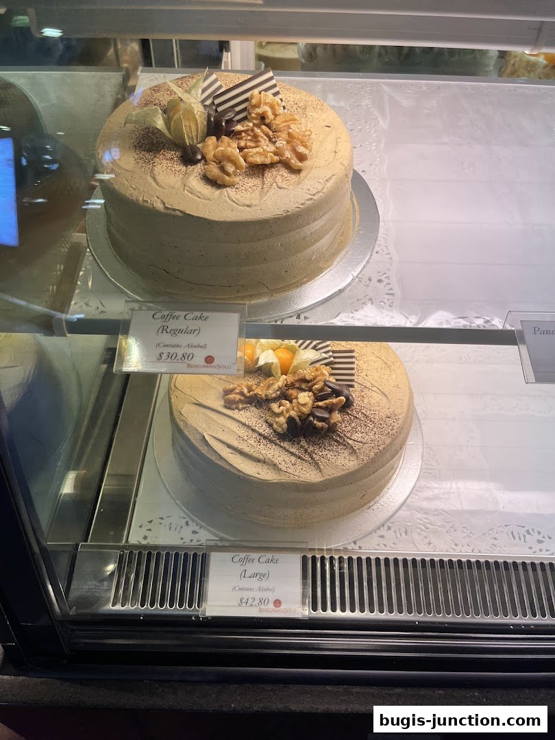 Two coffee cakes with walnuts and chocolate decorations displayed in a bakery case.
