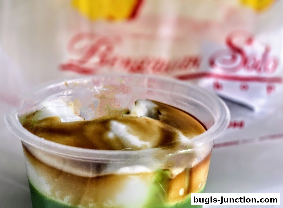 A close-up of a dessert in a clear plastic cup with the Bengawan Solo logo blurred in the background.