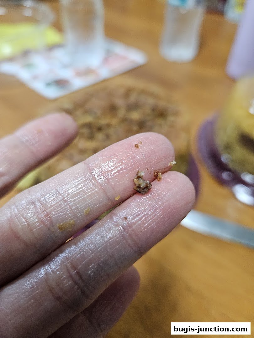 Close-up of crumbs on a finger with a blurred background of food and drinks.