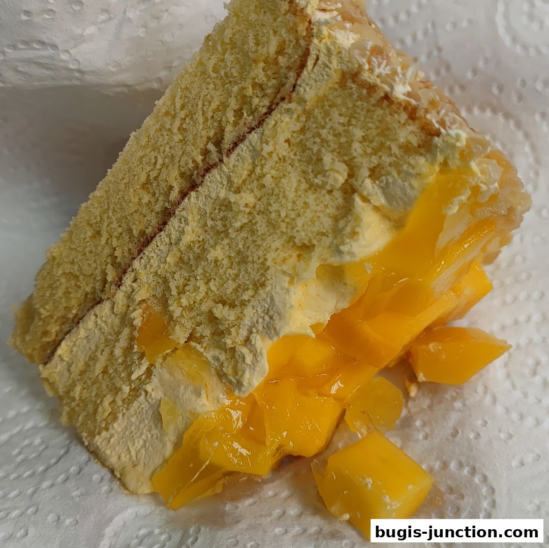A slice of moist cake filled with fresh mango chunks and cream.
