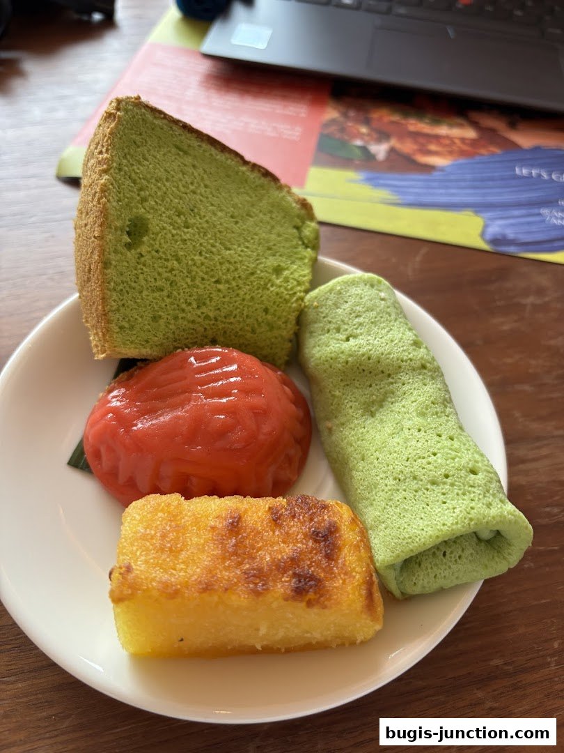 A plate of assorted traditional Indonesian kueh and cakes, including pandan cake and onde-onde.