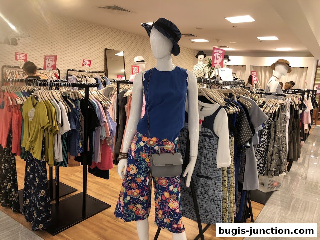 Mannequins display colorful clothing with sale signs in a well-lit retail store.