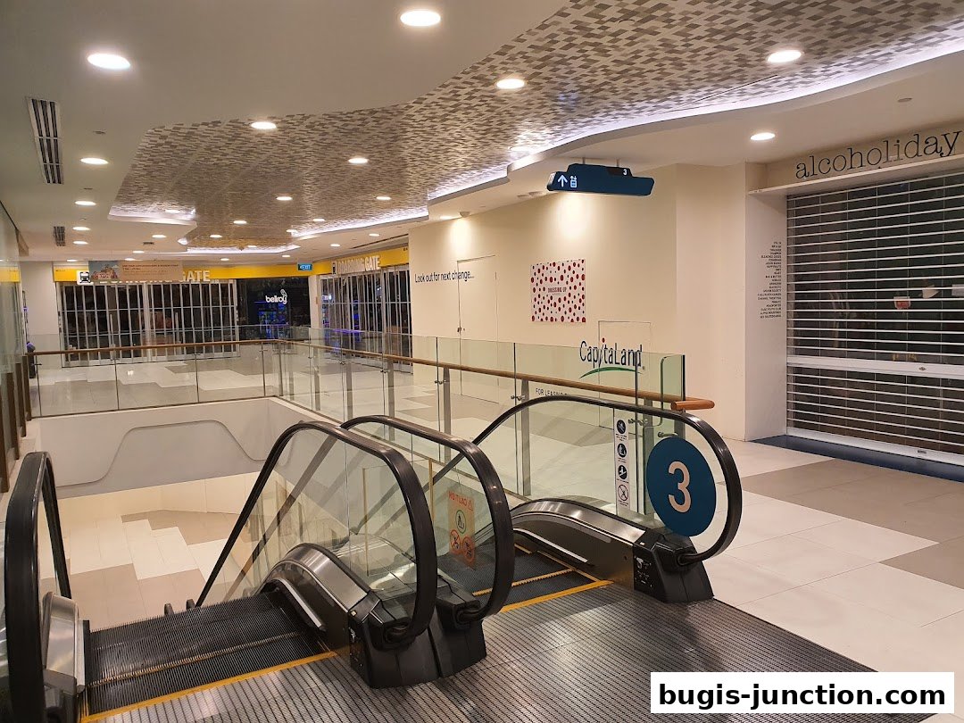 Interior view of a shopping mall with escalators and closed shop fronts.