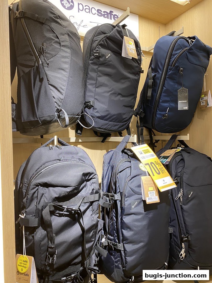 A display of various Pacsafe backpacks, some with sale tags.