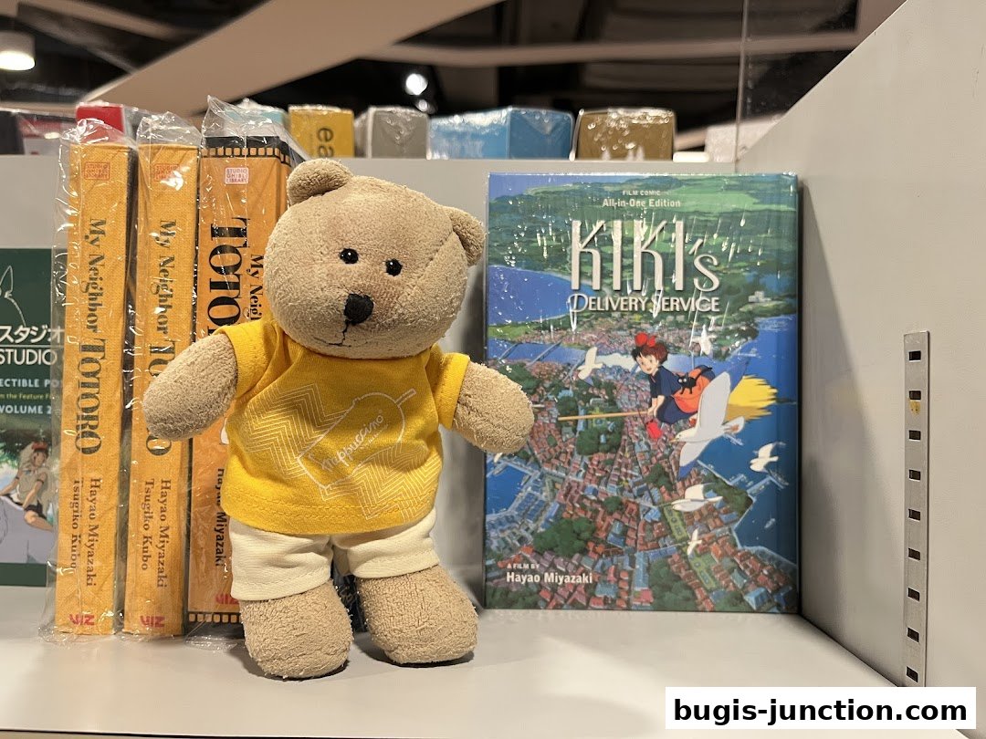 A teddy bear stands next to books featuring Studio Ghibli films, My Neighbor Totoro and Kiki's Delivery Service.