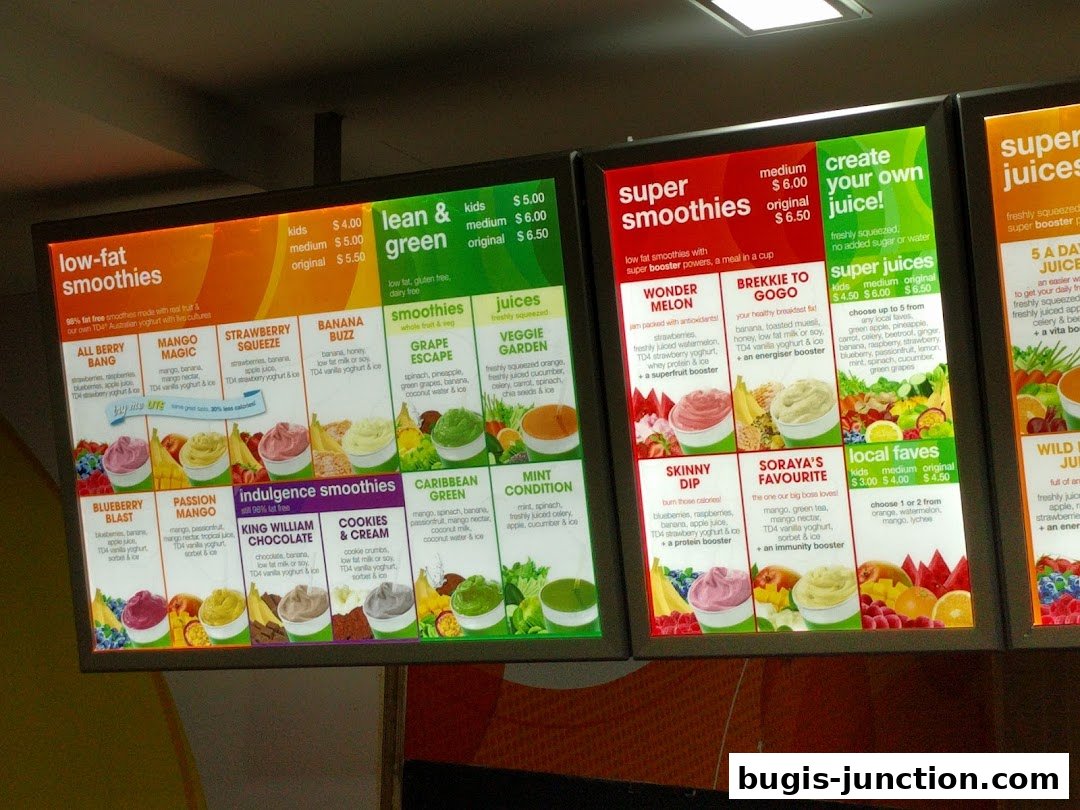 A brightly lit menu board displaying various smoothies, juices, and their ingredients.