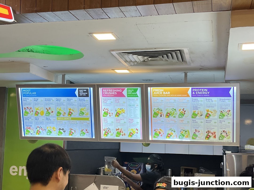 A brightly lit menu board displaying various juice and smoothie options categorized by popularity and benefits.