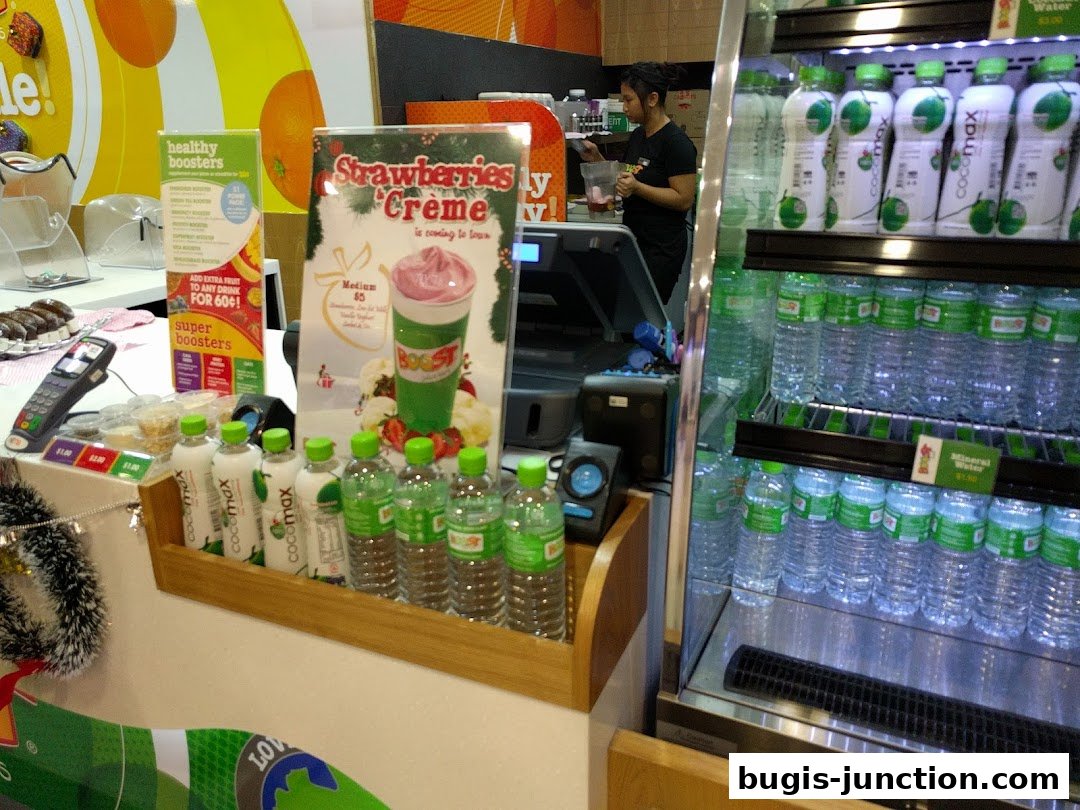 A Boost Juice counter with drinks, boosters, and a display for a new strawberry creme drink.