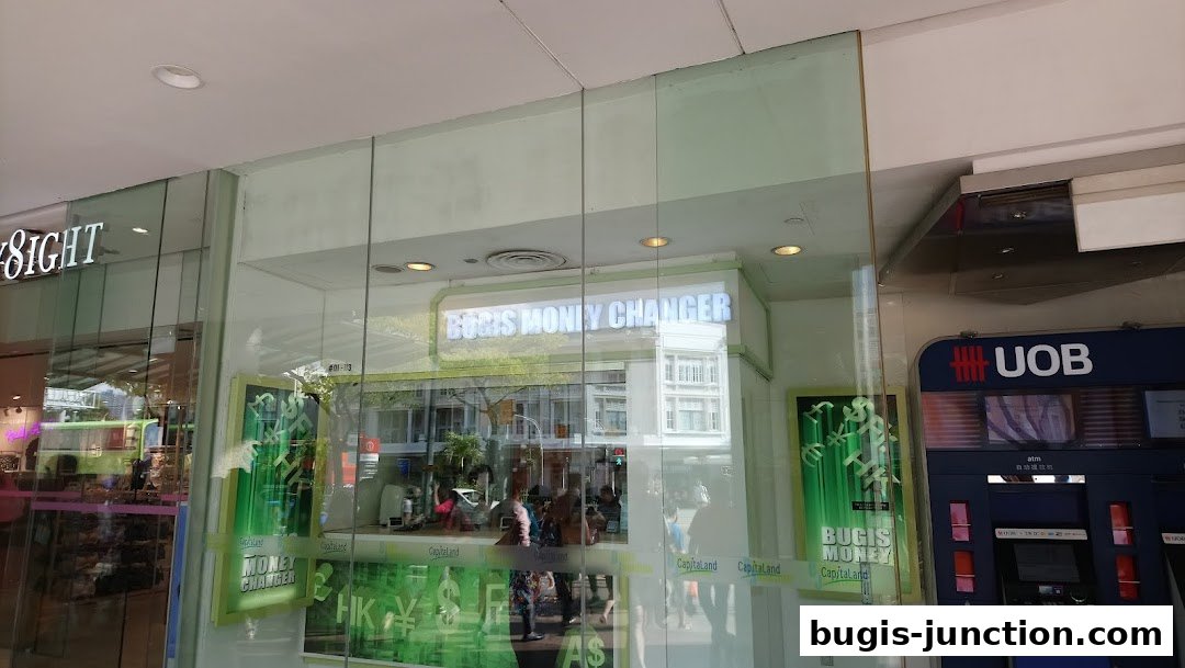 The exterior of Bugis Money Changer shop with its signage and currency symbols displayed.