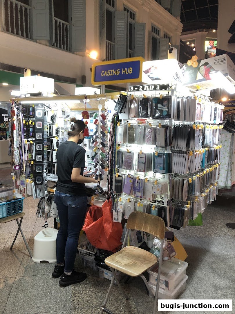 A person browsing a stall filled with phone cases and accessories.