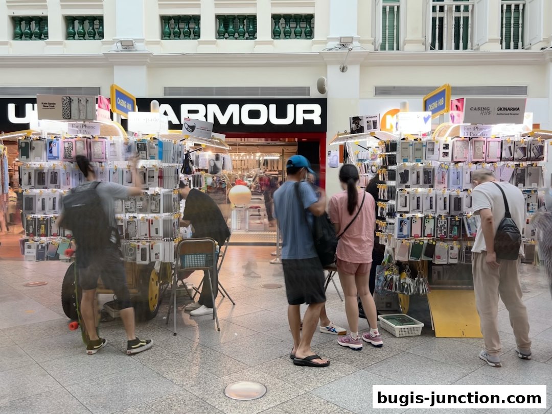 People browsing phone cases at a retail stall in a shopping mall.